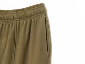 Detailed macro view of elastic waistband and pocket on olive green fleece trousers