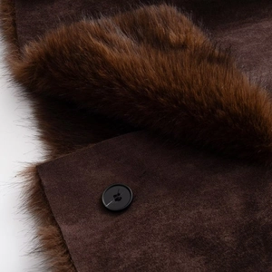 Detailed close-up of brown faux fur lining and suede fabric with a black round button