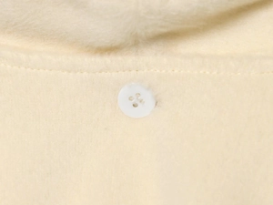 Detail of soft cream fleece fabric texture with a classic white four-hole button closure