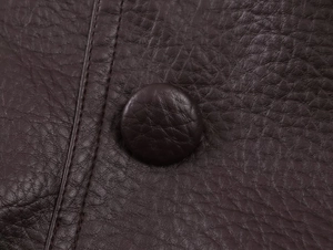 Détail de la veste en cuir marron avec bouton recouvert et coutures doubles nettes