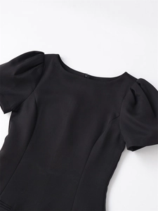 Detail view of the round neckline and puff sleeves on this slim black mini dress
