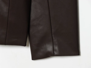 Close-up of dark brown PU leather jacket showing detailed lychee grain texture and stitching