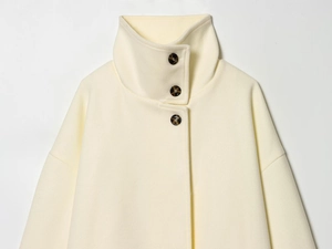 Detail of cream wool coat collar with tortoiseshell buttons and soft textured fabric