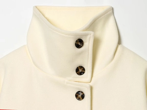 Detail of cream wool coat high stand collar with three tortoiseshell buttons
