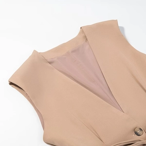 Detail of V-neck khaki vest showing a high-quality button and refined fabric texture