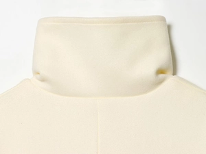 Close-up of the standing collar detail on the ivory wool-like coat with seamless stitching