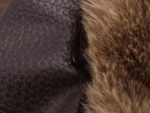 Détail macro de la texture en similicuir marron foncé et doublure en fourrure à bouton