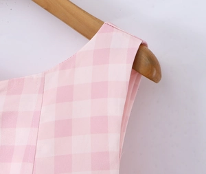 Detail of pink gingham dress neckline and fabric texture on a wooden hanger