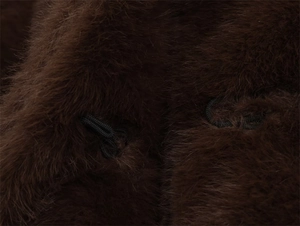 Détail de la texture en fausse fourrure marron et des boucles en corde de la veste