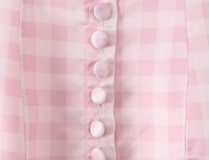 Detail of pink gingham fabric with matching fabric-covered buttons on a pleated dress