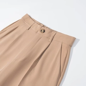 Detail view of khaki casual trousers with waist pleats, tortoise button and elastic waistband