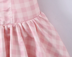 Detail of pink gingham dress featuring a high-waisted seam and dense pleated flare design