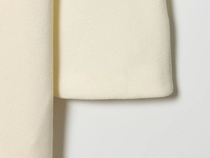 Macro shot of high-quality cream white wool blend fabric showing soft texture and fine stitching