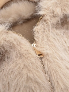 Close-up of beige faux fur texture with high-quality golden metal zipper detail