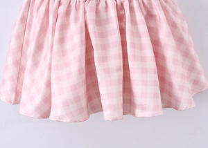 Close-up of pink and white gingham dress hem featuring soft ruffled edge detail