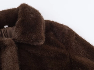 Détail de la veste en fausse fourrure marron montrant la texture douce et la doublure
