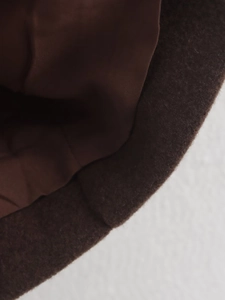 Detailed macro view of deep brown wool coat fabric texture and premium lining finish