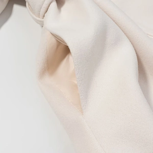 Close-up of premium wool blend fabric pocket with silky satin lining on a beige winter coat