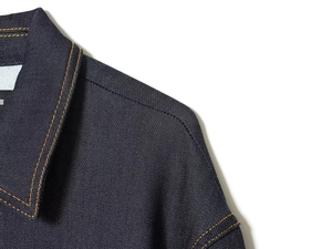 Detail of dark blue denim jacket neckline featuring contrast yellow stitching and twill texture