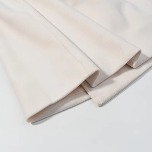 Detailed macro view of the premium wool fabric texture and clean hem stitching on the coat