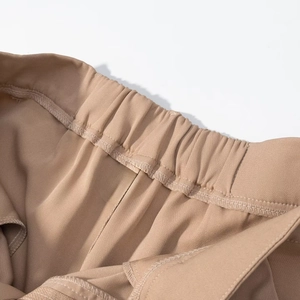 Detail of elastic waistband and precise inner stitching on khaki tailored trousers