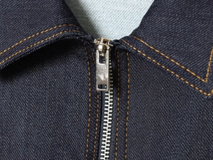 Close-up of dark blue denim jacket neckline with metal zipper and contrast stitching