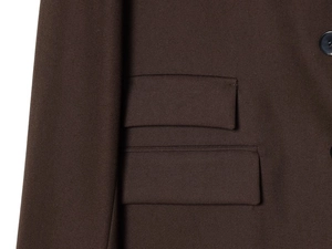 Détail des doubles poches à rabat et texture sergé fin sur une veste de blazer marron
