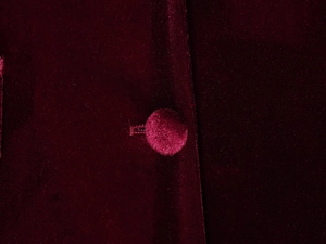 Dettaglio macro del bottone rivestito in tessuto e velluto su giacca bordeaux