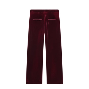 Dettaglio dei pantaloni in velluto bordeaux a vita alta con tasche a filetto e lucentezza