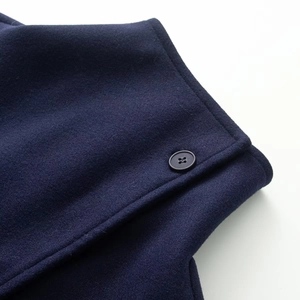 Dettaglio ravvicinato del tessuto lana blu navy e del bottone nero a quattro fori