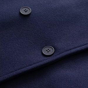 Dettaglio dei bottoni neri doppiopetto e della trama in lana blu navy di alta qualità