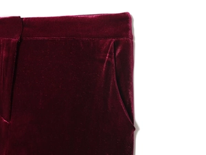 Dettaglio dei pantaloni in velluto bordeaux che mostra vita e tasca con lucentezza