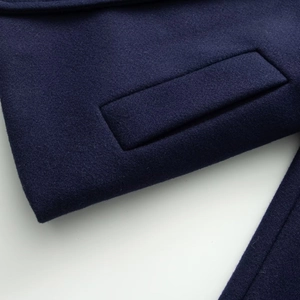 Dettaglio della tasca di un cappotto in lana blu navy con cuciture fini e trama del tessuto