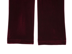 Dettaglio dell'orlo dei pantaloni in velluto bordeaux con cuciture e finitura lucida