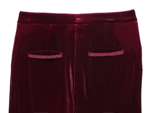 Dettaglio macro delle tasche posteriori dei pantaloni di velluto bordeaux con finitura lucida