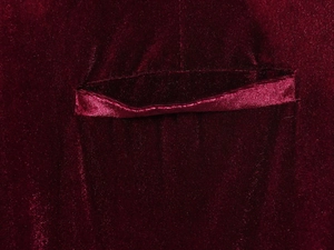 Dettaglio della giacca di velluto bordeaux con tasca che mostra trama di lusso
