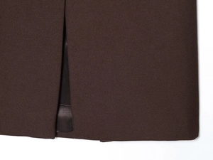 Détail macro de l'ourlet fendu et des coutures précises sur une veste de costume marron