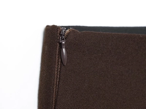 Détail de la fermeture éclair invisible sur le tissu texturé marron foncé de l'ensemble