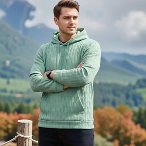 Gros plan d'un sweat à capuche vert clair avec texture plissée et poche kangourou