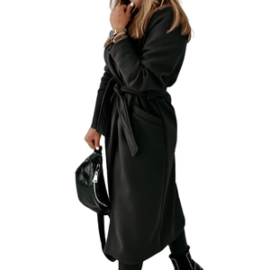 Detail of long black wool coat featuring a wide lapel and belted waist closure