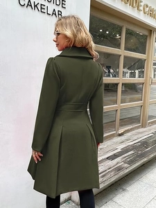 Detail van een legergroene wollen jas met tailleriem en elegante A-lijn plooien op de achterkant
