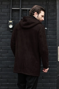 Back view of a men's dark brown hooded faux suede jacket in a stylish industrial setting