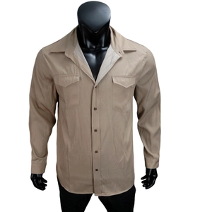 Detail of khaki long sleeve men's shirt showing buttoned chest pockets and pointed collar