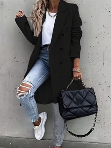 Street style shot of black double-breasted coat with blue ripped jeans and chain handbag