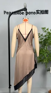 Detail view of champagne satin dress back featuring black mesh trim and asymmetric hemline