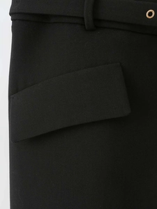 Detail of black mini dress featuring metal eyelet belt and structured pocket flap