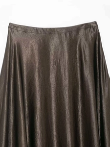 Détail de la texture satinée et du fini métallique sur le tissu d'une jupe marron