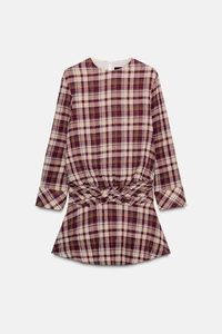 Detail of the twisted waist design on a red and black plaid mini dress with long sleeves
