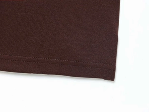 Detailed macro view of the double-stitched hem on a brown knitted midi dress fabric