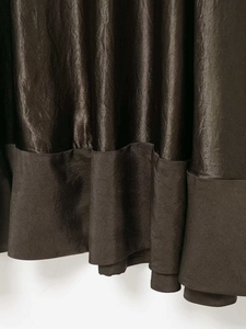 Vue détaillée de la texture satinée bronze et de l'ourlet plissé de la jupe midi
